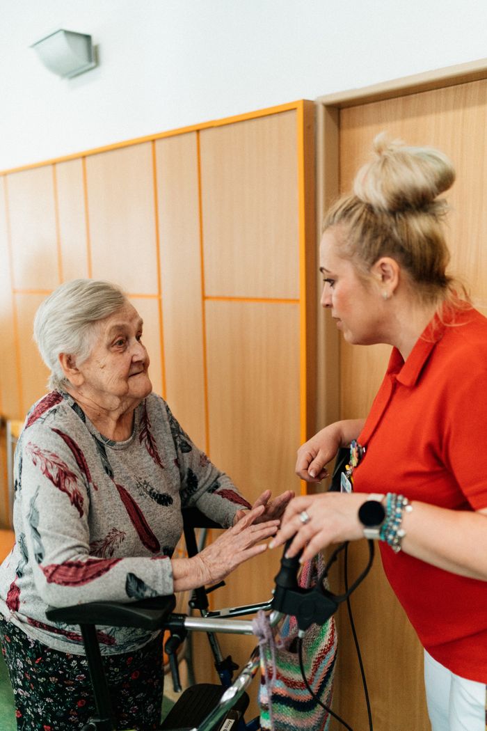 Home A caregiver assists an elderly woman in a retirement home corridor, fostering companionship and support.